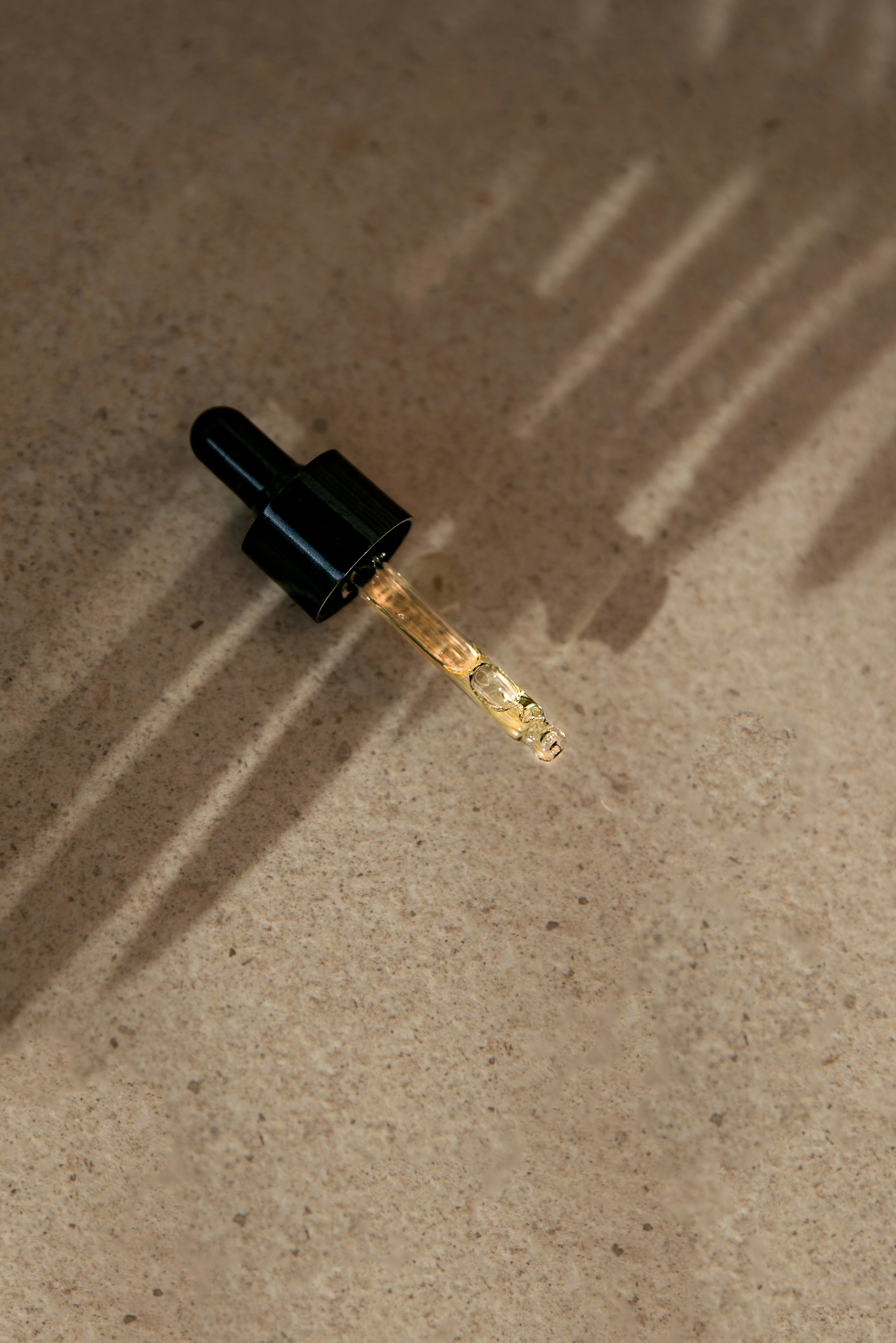Serum dropper with golden liquid on a stone surface