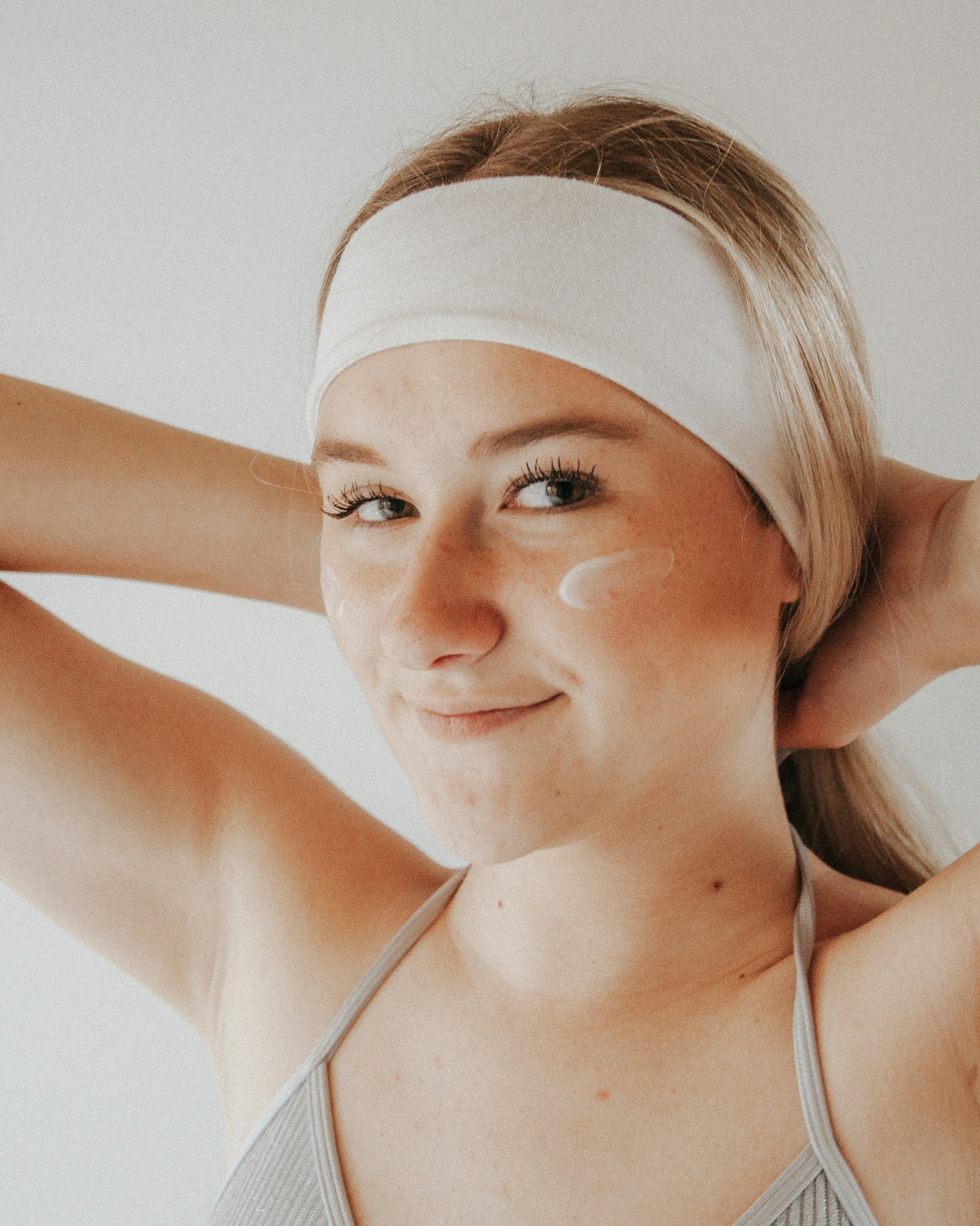 Woman with headband applying skincare cream