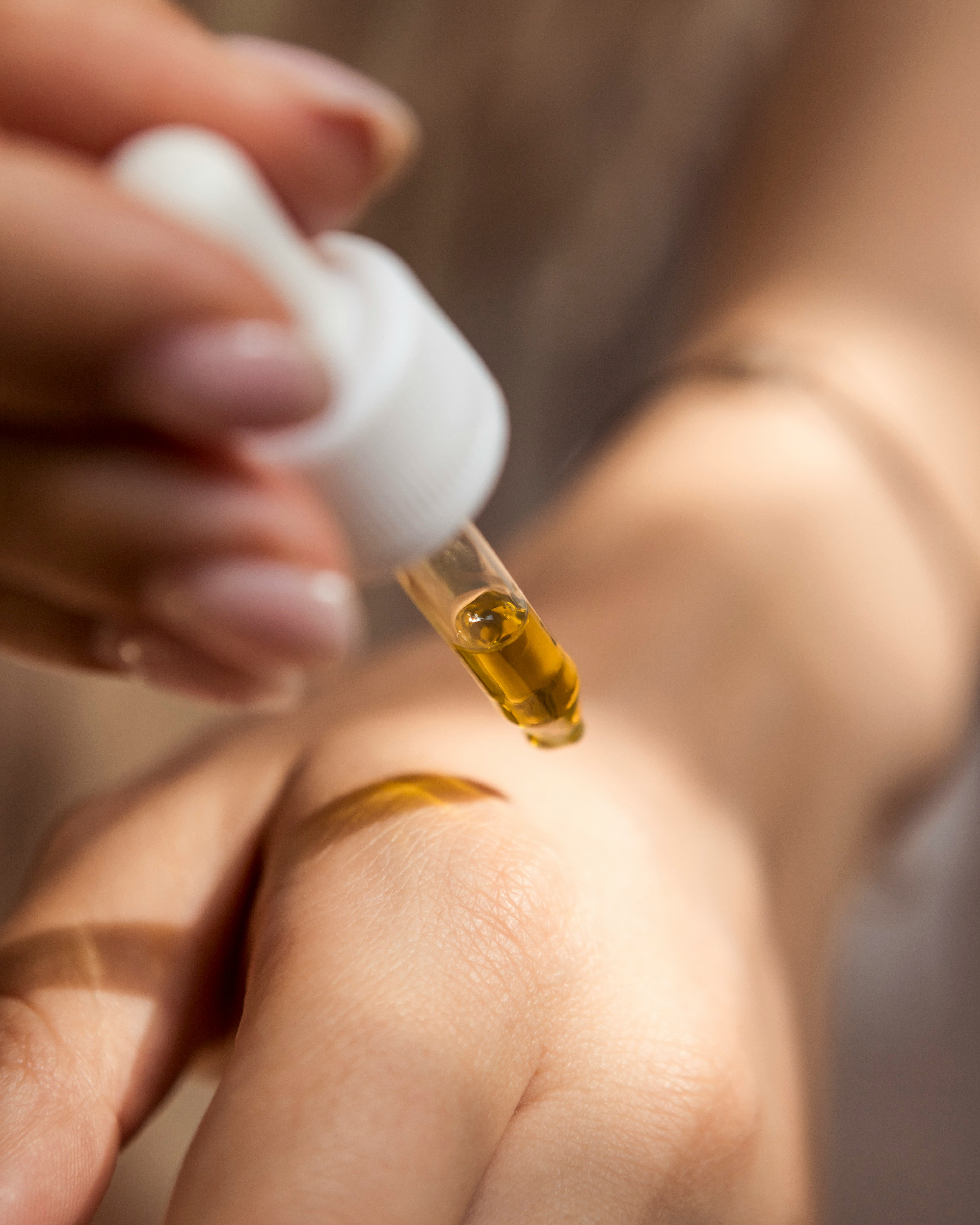 Golden serum being dropped from a pipette onto a hand