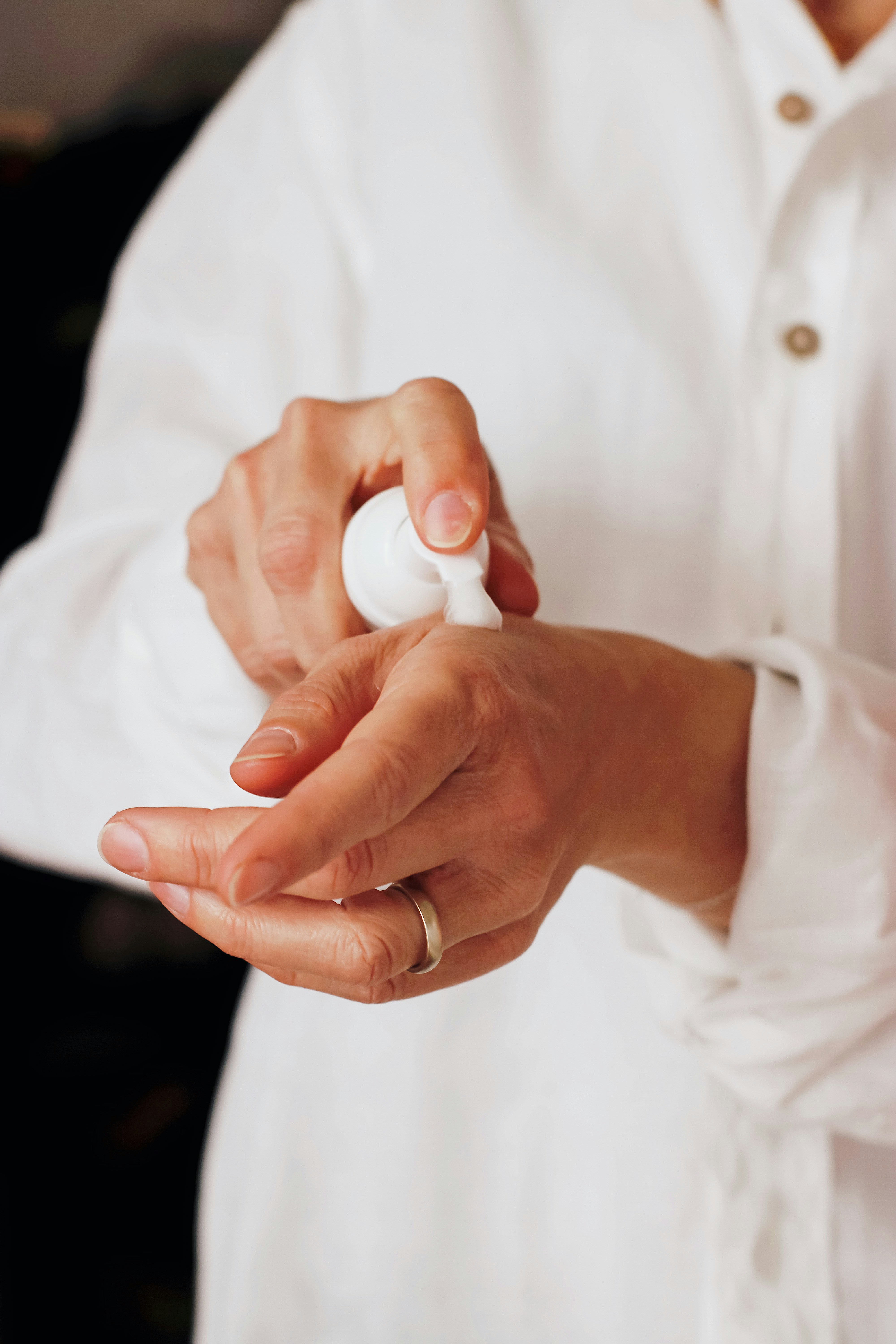 Hands applying moisturiser from a pump dispenser