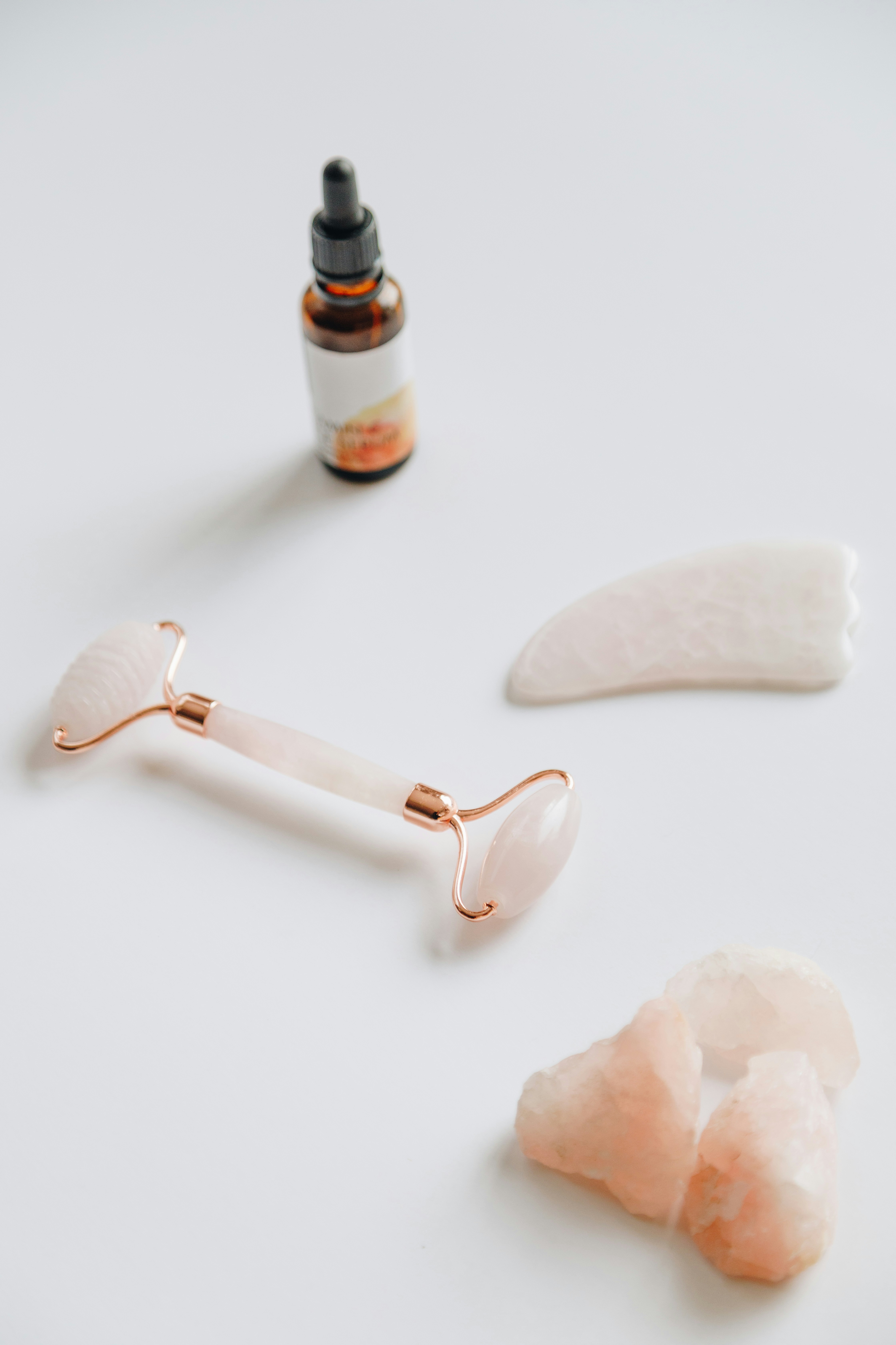 Rose quartz face roller and gua sha stone with serum bottle